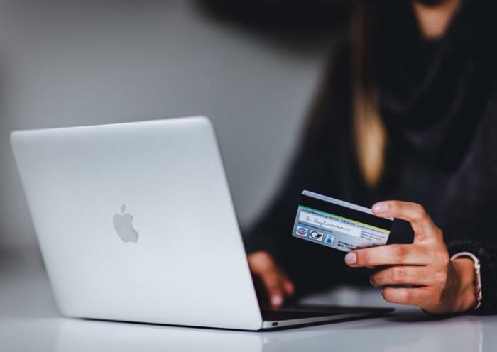 Mujer con su tarjeta de crédito frente a la notebook