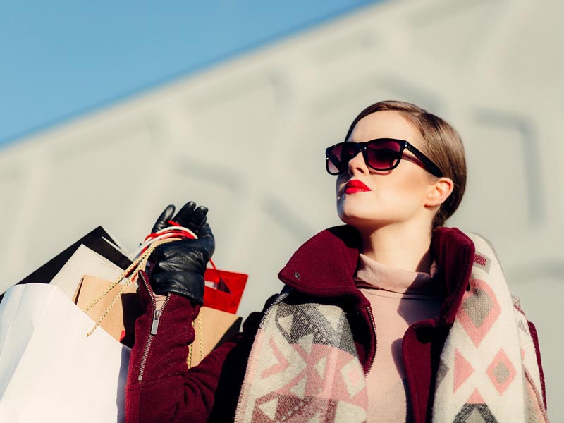Mujer haciendo compras shopping con lentes de sol y bolsas